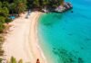 10 Secret Destinations for the Ultimate Budget Travel Experience Turquoise Albanian beach with backpacker.