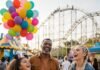 Top 10 Family-Friendly Travel Destinations for 2025 Laughing family at theme park with roller coaster and balloons.